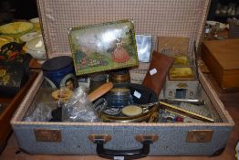 A suitcase containing an assortment of vintage items including a work box, enamel lidded jars, brass