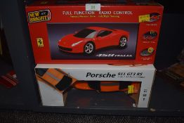 Two remote controlled cars in boxes, a Porsche 911 GT3 and a Ferrari 458 Italia.