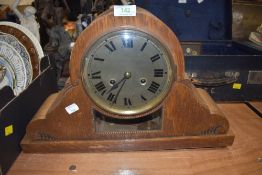 An ornate oak framed mantle clock having glass window and visible mechanism with chime