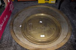 A large vintage brass Eastern styled table top and an embossed platter, possibly London scene.