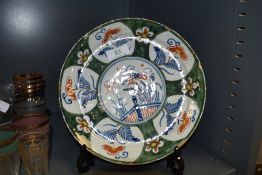 An antique Dutch delft plate with unusual green ground under typical blue and red colour ways and