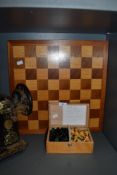 A wooden chess board and box of chess pieces.