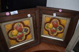 Two framed antique tiles depicting a variety of fruit.