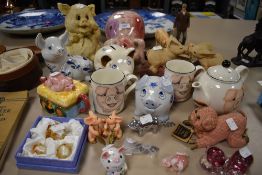 A collection of pig themed ceramicas and similar among which are also a cork screw, glass figures