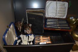 A metal deed box or tin with an assortment of vintage boxed cutlery, including cake forks, also
