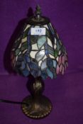 A modern Tiffany style lamp having brass stem and purple,pink and blue green hues to shade.