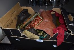 A box of leather and suede off cuts and a tin containing tools such as crotchet hooks, tape measures