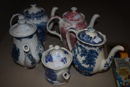 Four tea pots having blue and white transfer patterns and one with red and white pattern amongst