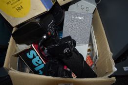 A box of various flashguns, lenses, filters, computer speakers etc
