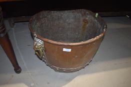 A traditional copper cauldron, having brass lion mask handles, drainage holes drilled to base,