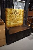 An early 20th Century dark oak box settle, having carved back and lower panels, width approx. 130cm