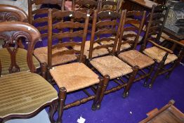 A set of six plus carver dining chairs having rush seats with traditional ladder back design