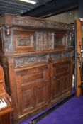 A period oak court cupboard having extensive carved detail to panels depicting wyvern or dragons
