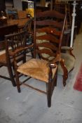 A traditional oak ladder back rush seated country carver chair