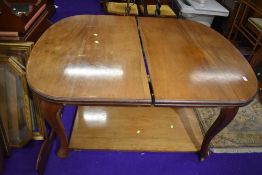 A light stained mahogany winding dining table with leaf