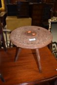 An Eastern style carved stool or occasional table on tripod legs