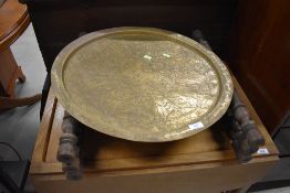 An Eastern carved brass top folding table, top a bit bashed and some of inlay missing, diameter