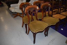 A set of four mahogany dining chairs having balloon backs with extensive carved detailing