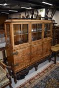 An early 20th Century walnut triple display with cupboard under, on ornate base, width approx.