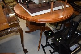 A modern extending dining table, in a light colour, having shaped edge, possibly Rossmore or similar
