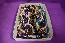 A box of costume jewellery strings of beads of various designs