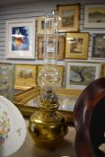 An antique brass desk top oil lamp with glass chimney.