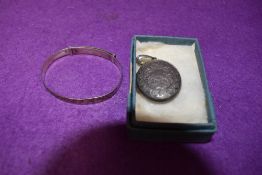 An HM silver locket of oval form having engraved foliate decoration and a white metal christening