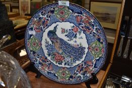 A mid century Japanese export display plate having transfer pattern depicting peacock and peonies.