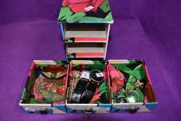 A miniature cardboard chest of drawers containing a small selection of costume jewellery including