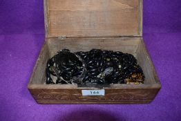 A carved treen box containing a selection of costume jewellery including two mourning jewellery muff