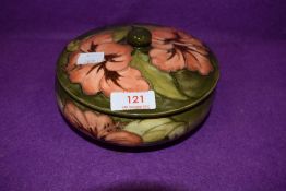 A vintage Moorcroft lidded bowl having orange hibiscus pattern on green ground.