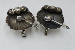 A pair of Victorian silver salts in the form of scallop shells on trefoil mythical fish feet,