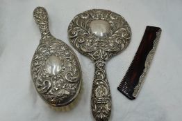 A silver three piece dressing table set having mask bird and scroll moulded decoration, Birmingham