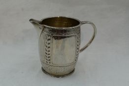 An Arts & Crafts silver cream jug by Liberty & Co having hammered and pressed leaf and dot