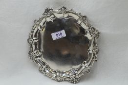 A Georgian silver card tray having decorative pie crust rim, trefoil hoof feet and bearing