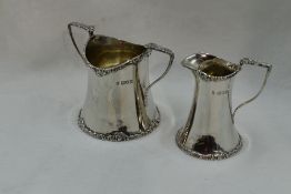 An Edwardian silver cream jug and sugar bowl of plain waisted form having moulded decoration to