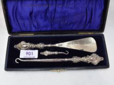 A cased Edwardian silver trio set of button hooks and shoe horn having moulded silver handles,