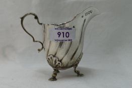 A Victorian silver cream jug having trefoil scallop and hoof feet, loop handle and line
