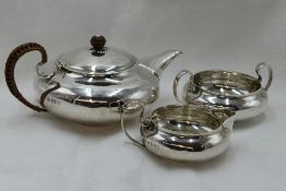 A silver three piece silver breakfast set of plain compressed circular form having wicker handle and