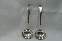 A pair of Georgian silver ladles of plain form bearing sun burst crest to terminals, London 1802,