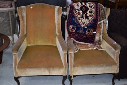 A pair of heavy framed wing back chairs, in the Queen Anne style, later ochre dralon upholstery