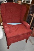 A modern wing back armchair in wine red upholstery