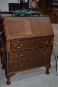 An early 20th Century mahogany bureau having flap top, three long drawers on ball and claw feet,