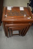 A vintage Oriental nest of four tables having carved and glazed tops, bottom table has no glass top