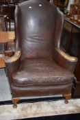 An early 20th Century leather wing back armchair, used patina
