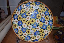 A colourful charger having hand painted floral design,indistinctly signed to underside.
