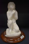 A carved figurine of praying child on wooden mount.
