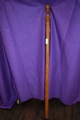 A walking cane with carved handle depicting a head.
