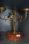 An arts and crafts brass candlestick holder having three swinging arms with ivy decoration and cross