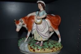 A Staffordshire style figurine depicting milk maid and cow.